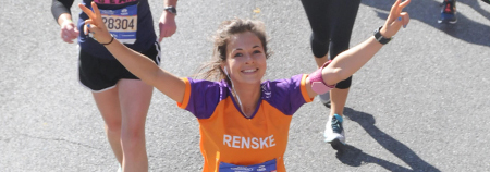 gefinishte marathon deelnemer in oranje/paars kika shirt, handen omhoog