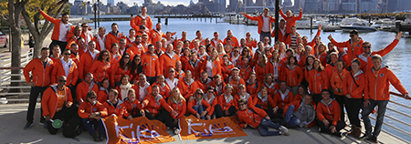 Groep Run for KiKa Marathon deelnemers in oranje jassen met twee KiKa vlaggen 